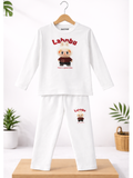 White pajama set with cartoon character and 'Lahnbu' text on a wooden stand with plants in the background.